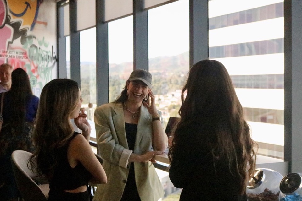 Alpha Team members and builders in conversation by the windows during an evening salon mixer at our Wilshire Boulevard headquarters