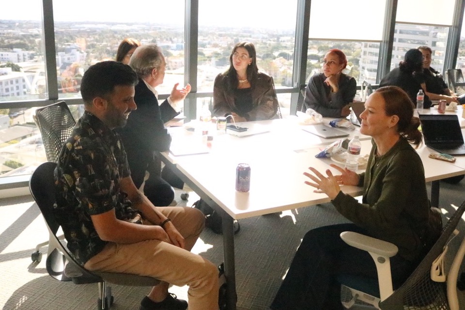 Builders and Alpha Team members collaborating around laptops during a daytime working roundtable at our Wilshire Boulevard headquarters